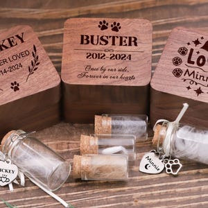 Puede incluir: Cajas conmemorativas de madera para mascotas con nombres y fechas grabados, junto con pequeños frascos de vidrio con tapones de corcho. Cada caja está personalizada con textos como "Mickey Forever Loved" y "Love Minnie".