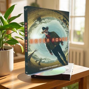 May include: DVD case for the TV show "Outer Range" featuring a man in a cowboy hat standing in front of a swirling landscape. The case says "The Complete Seasons 1-2".