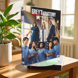 Peut inclure: Coffret DVD de Grey's Anatomy, les dix-neuf saisons complètes. La boîte présente un groupe d'acteurs en blouse, debout sur un escalier. Le titre "GREY'S ANATOMY" est imprimé en rouge et blanc sur la face avant de la boîte.