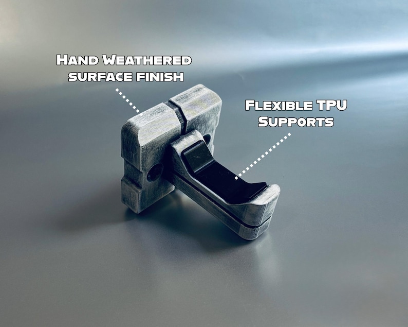 May include: A grey, rectangular object with a hand-weathered surface finish and flexible TPU supports. The text "HAND WEATHERED SURFACE FINISH" and "FLEXIBLE TPU SUPPORTS" are visible. The object is designed to hold something.