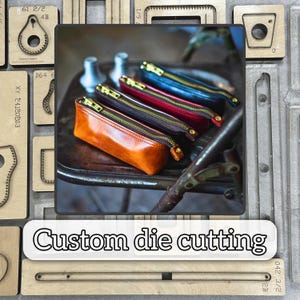 Può includere: Una collezione di astucci in pelle di vari colori, tra cui arancione, rosso, blu e marrone, con cerniere dorate. Gli astucci sono esposti su una sedia vintage. L'immagine include anche il testo "Custom die cutting".