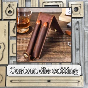 May include: A brown leather cigar case with two compartments, open to display two cigars. The case is on a wooden surface, with a glass of amber liquid and a coaster in the background. The text "Custom die cutting" is displayed.