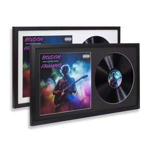 May include: Black vinyl record frame with a black mount and a clear acrylic insert. The frame is displaying a record with a colourful album cover featuring a person playing a guitar. The album cover text reads "BOLDON VINYL RECORD FRAME FRAMING".