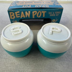 May include: Vintage Bean Pot salt and pepper shaker set in turquoise and white with the letters "S" and "P" on the lids. The shakers are in their original box.