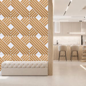 Puede incluir: Un panel de pared con un patrón geométrico repetitivo de listones de madera de color marrón claro en relieve dispuestos en líneas diagonales sobre un fondo blanco, situado detrás de un banco rectangular capitoné de color crema.