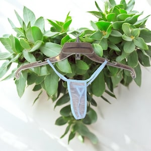 May include: A light blue sheer lingerie garment hanging on a plastic hanger. The garment is made of a delicate, see-through fabric with a simple design.