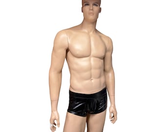 May include: A male mannequin with a light skin tone and defined muscular physique, wearing black, form-fitting, glossy, wet-look boxer briefs with a low-rise waistband. The garment features a smooth, reflective surface texture.