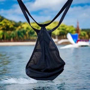 May include: A black mesh sling bag hanging over a body of water. The bag is suspended by two straps and has a triangular shape.