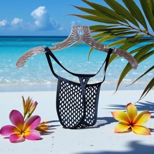 May include: Black mesh thong underwear hanging on a clear plastic hanger. The underwear is displayed on a white sandy beach with a tropical ocean background. Pink and yellow flowers are in the foreground.
