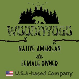 Pu&ograve; includere: Uno sfondo verde con una silhouette nera di una foresta e un orso. Il testo "WOODAYOGO" &egrave; in nero con un aspetto usurato. Sotto il testo si trovano "NATIVE AMERICAN" e "FEMALE OWNED" in nero. Il testo "U.S.A.-based Company" &egrave; in nero con una piccola bandiera americana a sinistra.