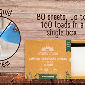 Pu&ograve; includere: Una scatola marrone con un'etichetta bianca che dice "Woodayogo Laundry Detergent Sheets Fresh Air 80 Sheets Up to 160 Loads". La scatola &egrave; aperta e mostra una pila di fogli di detersivo per il bucato bianchi. La scatola &egrave; su una superficie di legno. L'immagine mostra anche un cerchio con una linea diagonale che lo attraversa, con una bottiglia di detersivo liquido per il bucato che viene versato in un dispenser di lavatrice. Il testo "No liquid No mess" &egrave; scritto attorno al cerchio.