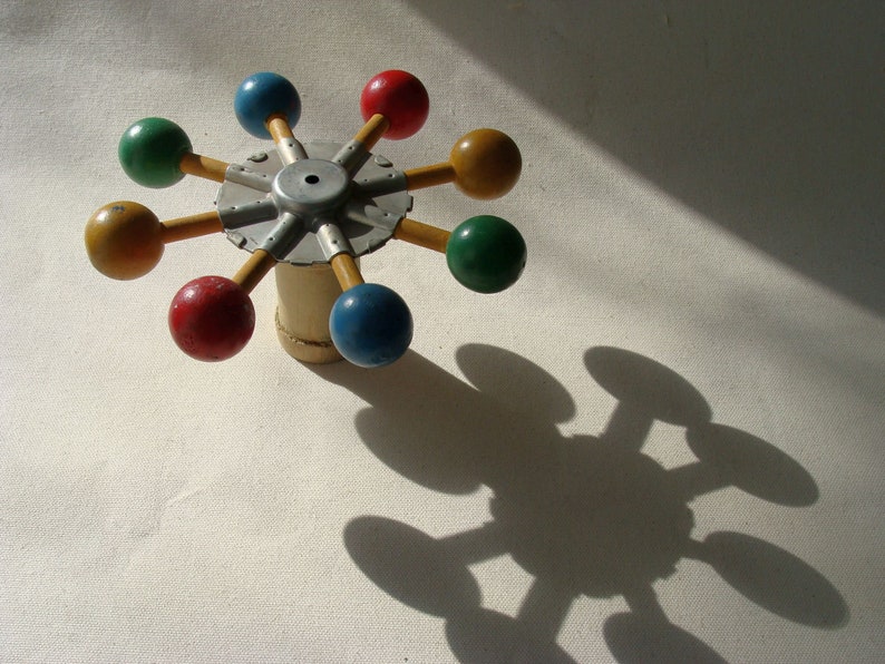 vintage wood and metal game or toy component with brighly painted balls which could easily be made to spin for hours of fun