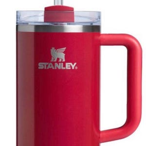 May include: A red stainless steel travel mug with a black handle and a black logo that says "STANLEY". The mug has a clear lid with a red straw.