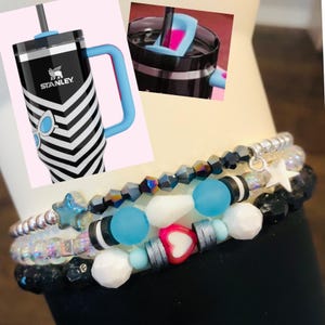 May include: A set of four bracelets with black, white, blue, and silver beads. The bracelets feature a heart charm, a star charm, and a variety of other beads.