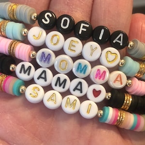 May include: A colorful bracelet with beads spelling out the names "Sofia", "Joey", "Momma", "Mama", "Sami" and two heart charms.
