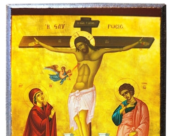 May include: A rectangular wooden icon featuring a religious painting of the crucifixion of Jesus on a cross against a gold background. The scene includes figures in red and pink robes, a small angel, and Greek text inscriptions.