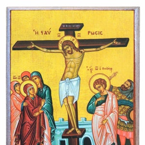 Puede incluir: Un icono religioso que representa la crucifixión de Jesucristo. El icono está pintado en un estilo tradicional con colores vibrantes. Jesús está representado en la cruz con una corona de espinas y sangre que fluye de sus heridas. El icono también presenta a María, Juan el Evangelista y un soldado romano.
