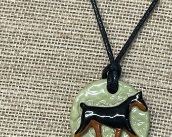 Doberman pendant in clay.  Green backround. Adjustable black cord necklace