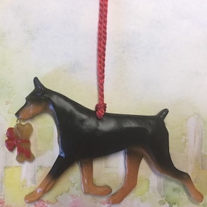 Doberman with bone. Black and tan. Artist sculpted dog breed ornament by Artdog Ornaments.