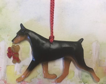 Doberman with bone. Black and tan. Artist sculpted dog breed ornament by Artdog Ornaments.