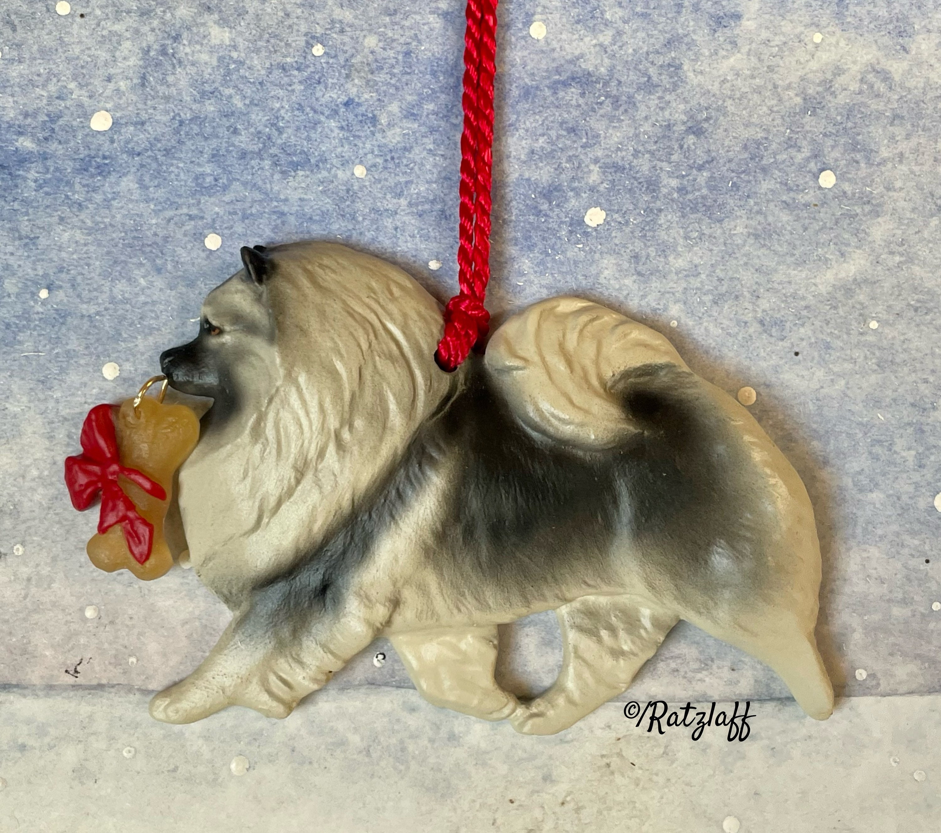 Keeshond with bone. Christmas/holiday artist dog breed ornament. Handcrafted by Artdog Ornaments.
