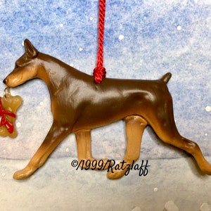 Doberman with bone. Red and tan. Artist sculpted dog breed ornament by Artdog Ornaments.