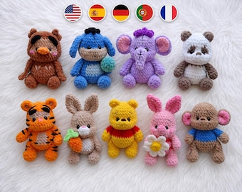 May include: A collection of nine small, handmade crochet plush toys featuring various animal characters including a brown bear, a blue donkey, a purple elephant, a panda, a tiger, a rabbit with a carrot, a yellow bear, a pink piglet, and a monkey.