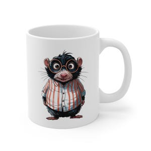 May include: White ceramic mug featuring a cartoon illustration of a rat wearing glasses and a striped shirt. The rat has black fur, pink ears, and is smiling. The mug has a standard handle and a glossy finish.