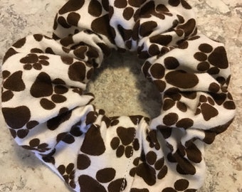 May include: White scrunchie with brown paw print pattern.