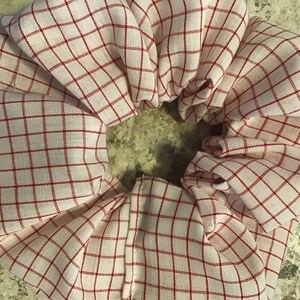 May include: A white and red checkered scrunchie. The scrunchie is made of fabric and has a red checkered pattern.