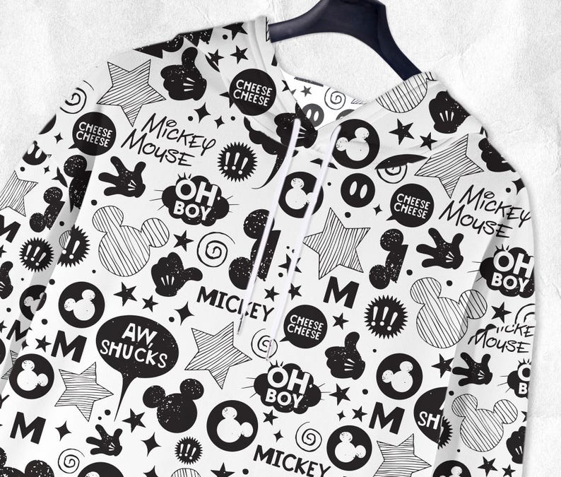 Peut inclure: Sweat &agrave; capuche blanc avec un motif Mickey Mouse noir et blanc. Le motif comprend des silhouettes de Mickey Mouse, des &eacute;toiles, des bulles avec des phrases comme "Oh Boy" et "Aw Shucks", et les mots "Mickey Mouse".