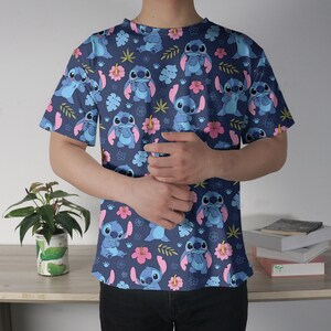 Pu&ograve; includere: Una maglietta blu navy a maniche corte con un motivo ripetuto del personaggio Stitch del film Lilo & Stitch. Il design include Stitch, fiori rosa e fogliame verde. La maglietta &egrave; realizzata in materiale morbido.