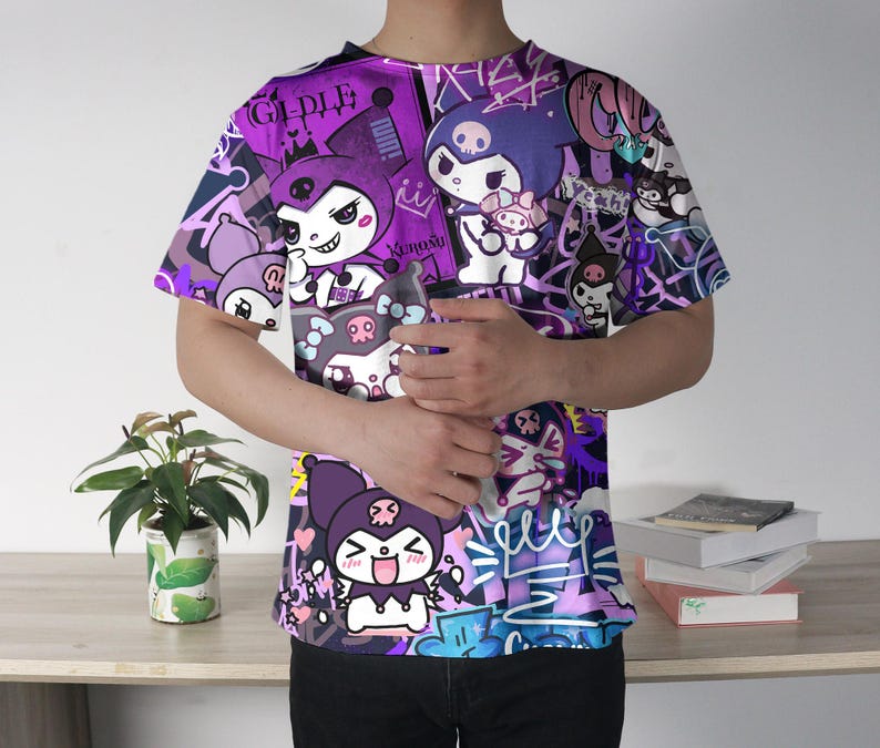 May include: A purple t-shirt with a cartoon character design, featuring illustrations and text. The short-sleeved shirt has a crew neck. The design incorporates shades of purple, white, and black.