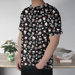May include: Black t-shirt featuring a repeating pattern of Hello Kitty characters in various Halloween costumes, along with spiderwebs and the text "Hello Kitty". The design is in white, red, and black.