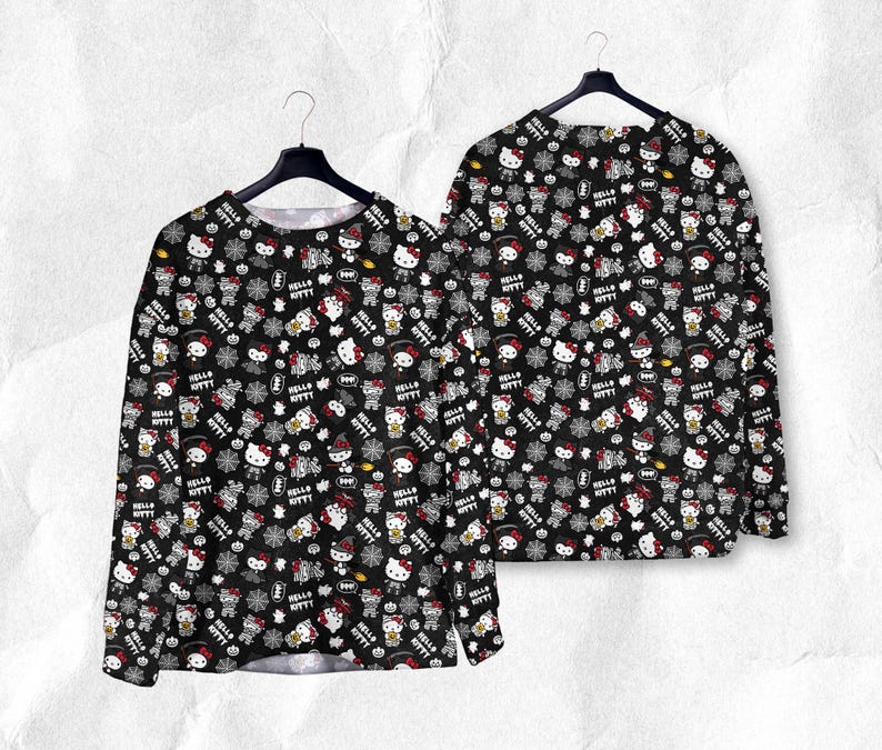 May include: Black long-sleeve shirt with a repeating pattern of Hello Kitty characters, snowflakes, and text. The design includes red, white, and gray elements on a black background. The shirt is displayed on a hanger.