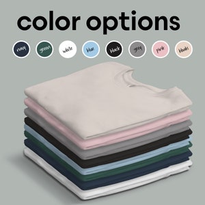 May include: A stack of folded t-shirts in various colors, including white, pink, grey, black, blue, green, and navy. The colors are displayed in a row above the stack of shirts. The text "color options" is displayed above the colors.