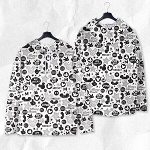 Peut inclure: Deux chemises &agrave; manches longues avec un motif Mickey Mouse noir et blanc. Le motif comprend des visages de Mickey Mouse, des &eacute;toiles, des bulles et les phrases "Mickey Mouse", "Oh Boy" et "Aw Shucks".