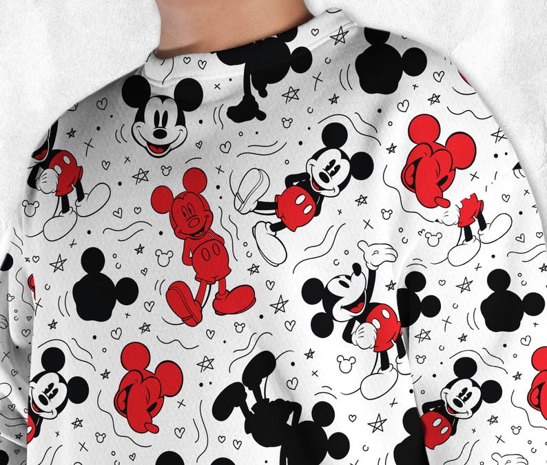 May include: White sweatshirt with a repeating pattern of Mickey Mouse in various poses, black Mickey Mouse silhouettes, red shorts, hearts, stars, and other small shapes. The sweatshirt has a crew neck.