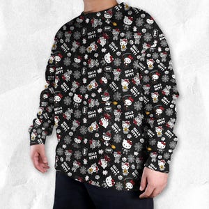 May include: Black long-sleeve shirt with an all-over print featuring Hello Kitty characters in Halloween costumes, pumpkins, spiderwebs, and the text "Hello Kitty". The design includes red, white, and black elements.