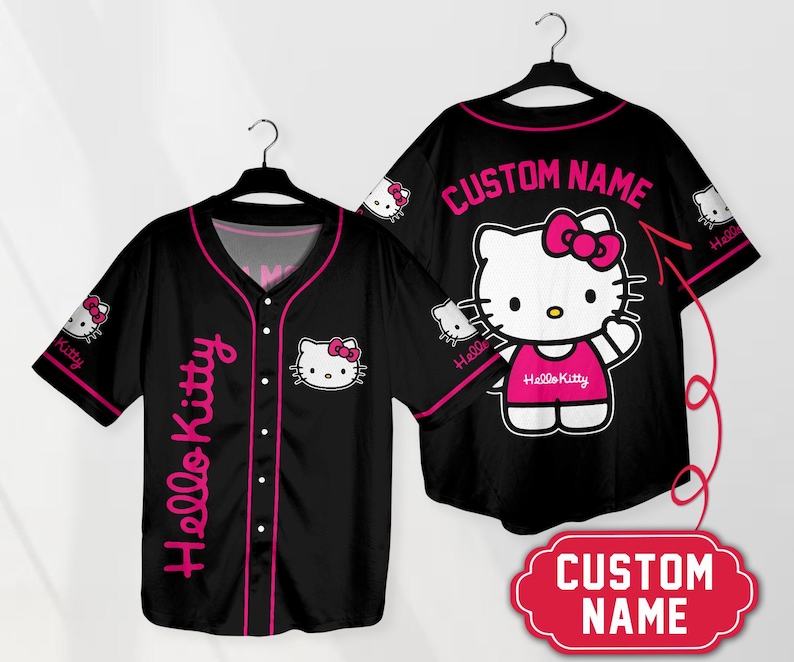 Puede incluir: Camiseta de b&eacute;isbol negra con gr&aacute;ficos de Hello Kitty. La camiseta tiene un ribete rosa, texto de Hello Kitty en el lateral y un gr&aacute;fico de Hello Kitty en la parte delantera. La parte posterior de la camiseta tiene un gran gr&aacute;fico de Hello Kitty y el texto "CUSTOM NAME".
