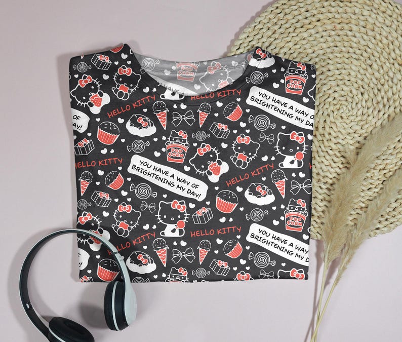 May include: Black t-shirt with a repeating pattern of Hello Kitty characters, cupcakes, ice cream cones, and candies. The shirt includes the text "Hello Kitty" and "You have a way of brightening my day!"