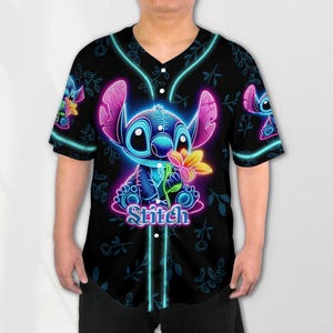 Puede incluir: Una camiseta de b&eacute;isbol negra con un personaje Stitch azul ne&oacute;n y rosa sosteniendo una flor. El texto "Stitch" est&aacute; impreso debajo del personaje.