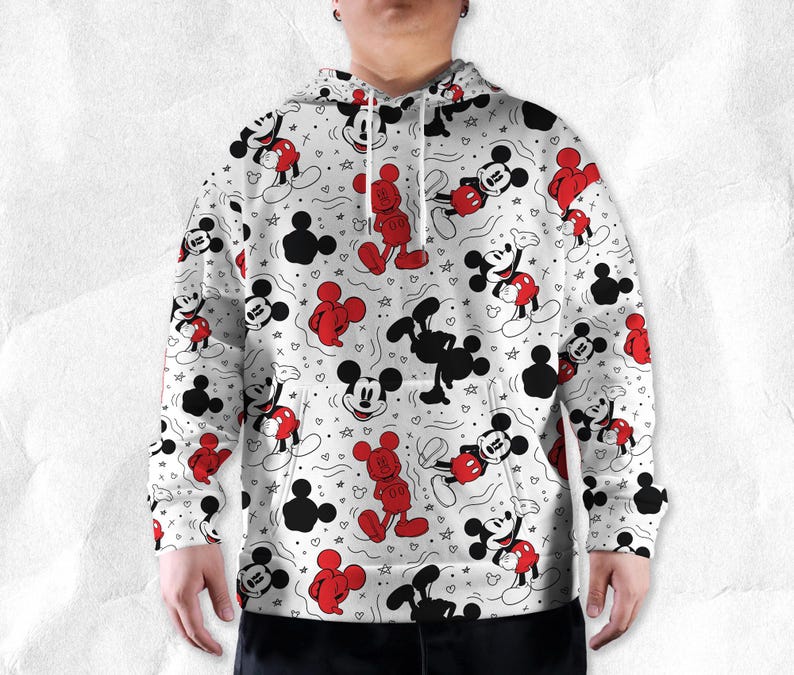 May include: White hoodie with a repeating pattern of Mickey Mouse in red, black, and white. The design includes various poses of Mickey, along with stars and hearts. The hoodie has a drawstring hood and a kangaroo pocket.