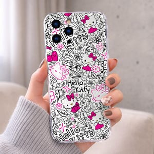 May include: Clear phone case featuring a white and black floral design with the words "Hello Kitty" and images of the character in pink. The case has a transparent border and is designed to fit a smartphone.