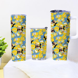 May include: Three beverage containers featuring a blue backdrop and a repeating pattern of yellow cartoon characters. The containers include a tall tumbler, a travel mug, and a handled mug. The mugs are cylindrical with a white handle.