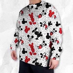 May include: White sweatshirt with a repeating pattern of Mickey Mouse in red, black, and white. The design includes full-body images, silhouettes, and Mickey Mouse heads, with hearts and stars scattered throughout.
