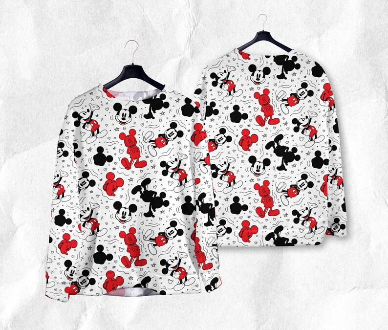 May include: White long-sleeved sweatshirt with a repeating pattern of Mickey Mouse in red and black, and black Mickey Mouse silhouettes. The design includes small stars and hearts. The sweatshirt is displayed on a black hanger.