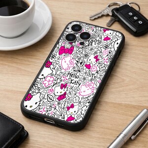 May include: Black iPhone case featuring a white background with a repeating pattern of Hello Kitty characters, flowers, and leaves, accented with pink details. The case has a black border and is shown on a wooden surface.