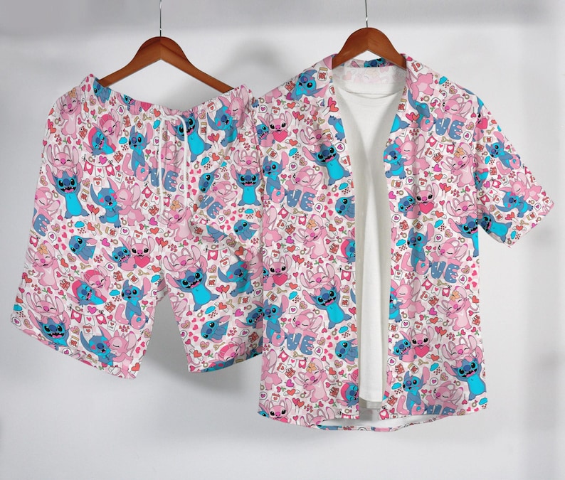 Puede incluir: Un conjunto de pijama a juego con un estampado rosa, azul y blanco de un personaje de dibujos animados y corazones. El conjunto incluye una camisa con botones, pantalones cortos y una camiseta interior blanca. La camisa y los pantalones cortos cuelgan de una percha de madera.