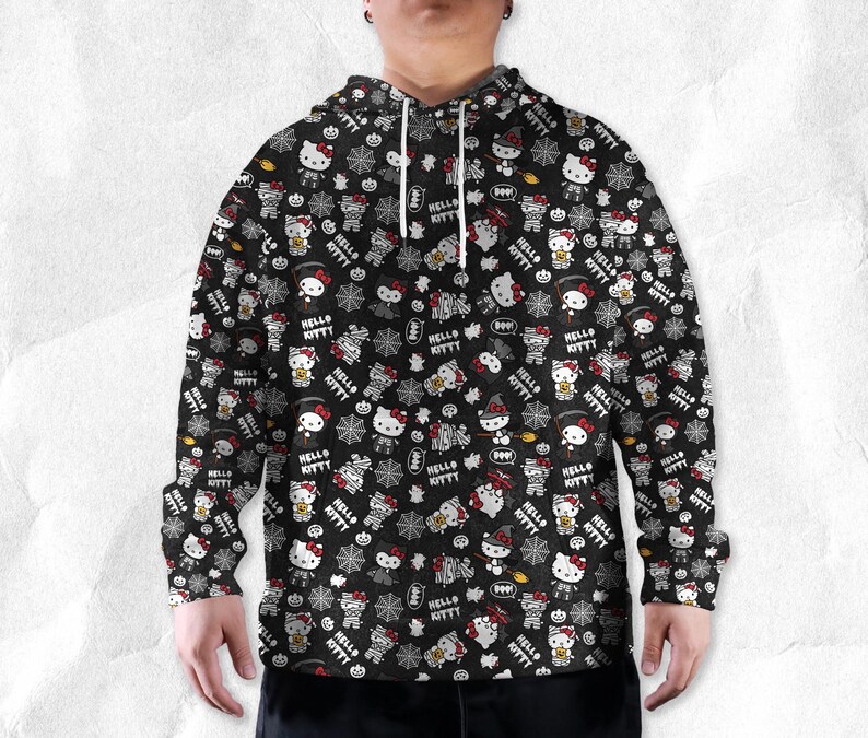 May include: Black hoodie with a repeating pattern of Hello Kitty characters in Halloween costumes, pumpkins, and spiderwebs. The words "Hello Kitty" are also printed throughout the design. The hoodie has a drawstring hood and long sleeves.